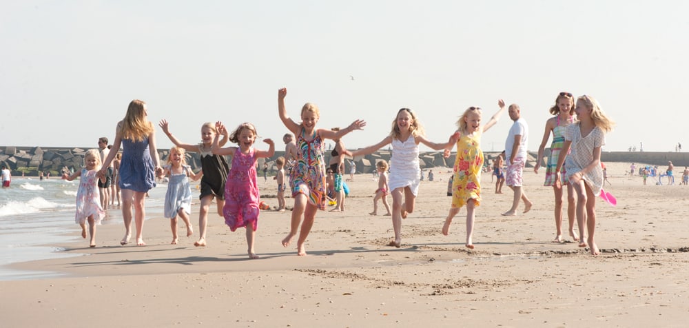 Kinderen rennen en juichen naast elkaar al rennend op het strand.